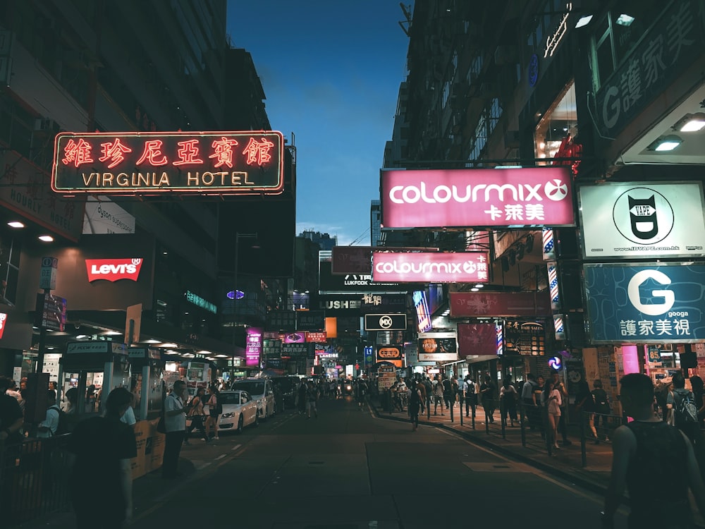 crowd walking on pathway surrounded by buildings during night time