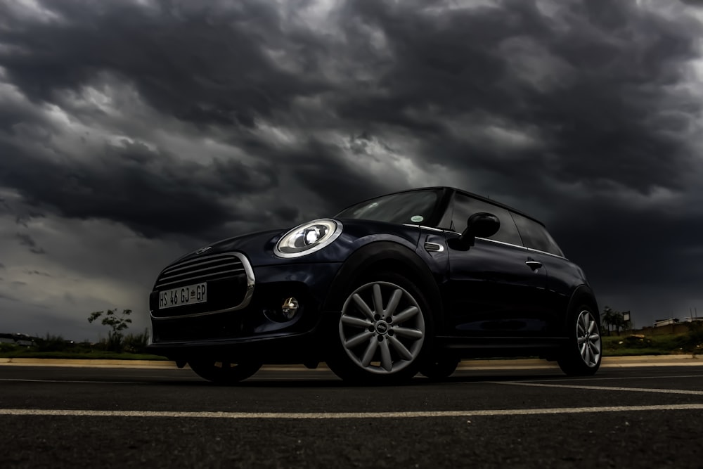 Mini Cooper hatchback negro de 3 puertas en la carretera bajo un día nublado