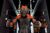 A menacing creature with multiple protrusions from its head stands in a futuristic corridor lined with metallic and glass elements. The creature's skin is textured and appears to have a reddish-brown tone, with sharp, claw-like fingers extended forward. The setting suggests a scene from a science fiction or horror genre.