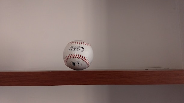 A neatly arranged display of baseballs on wooden shelves inside a cozy shop.