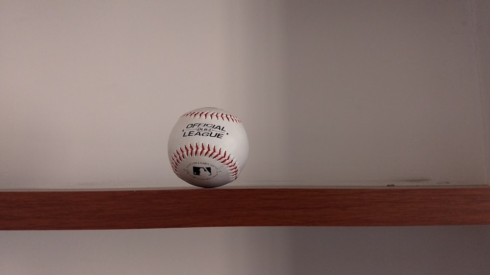 bola de beisebol branca no rack de madeira marrom