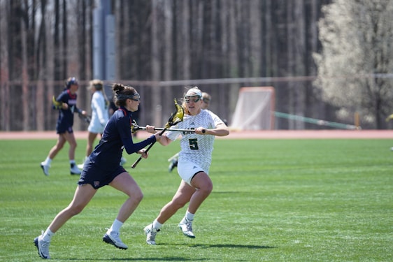 Action shot of Methacton Warriors lacrosse players in dark green and white uniforms fiercely competing during a game.