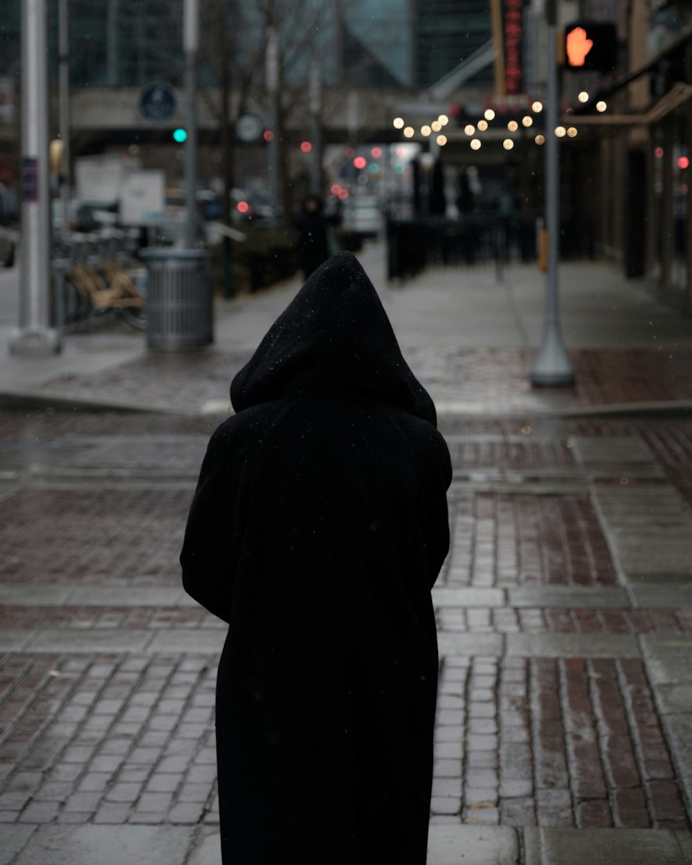 person wearing hooded coat walking towards traffic light