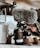 A professional camera equipped with a large, furry microphone is positioned on a surface. Surrounding items include components of a drone and some indistinct background elements, adding a tech-focused atmosphere.