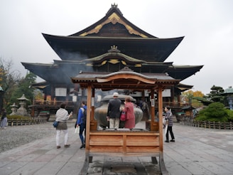 A peaceful temple courtyard with visitors lighting incense and praying