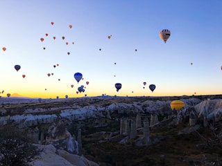 A colorful hot air balloon floating above the unique rock formations of Cappadocia at dawn.