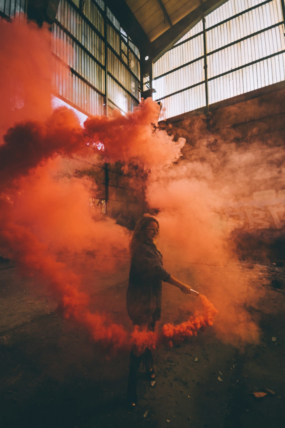 woman holding orange smoke bomb inside room