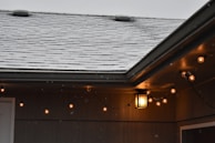 Bright string lights illuminating a snowy porch, adding a touch of warmth to the winter night.