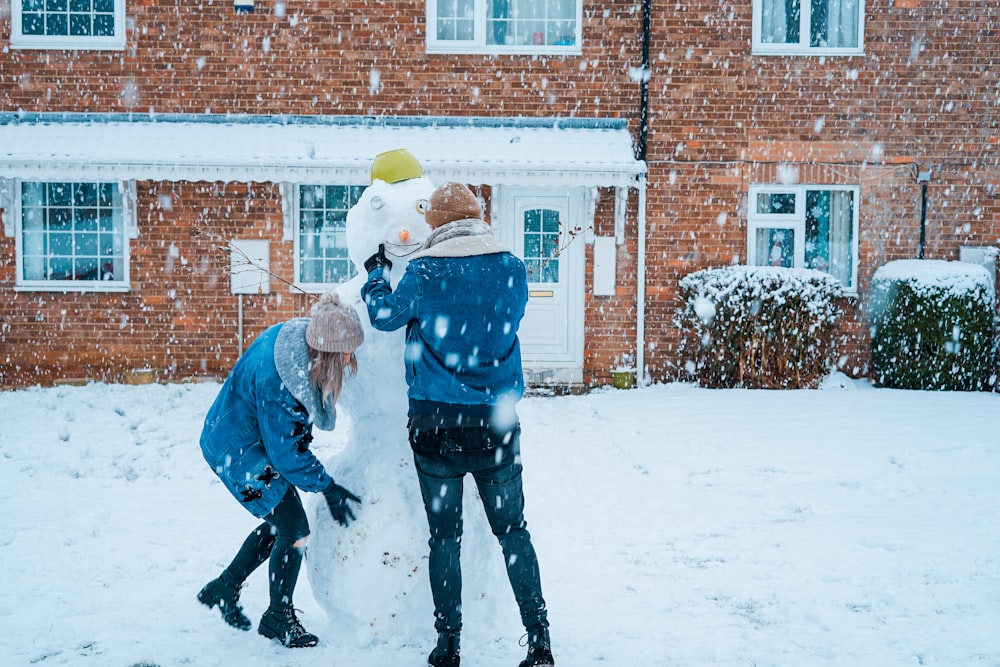 couple building snowman during winter