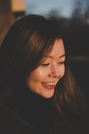 A smiling woman practicing mindfulness in a sunlit room, embodying peace.