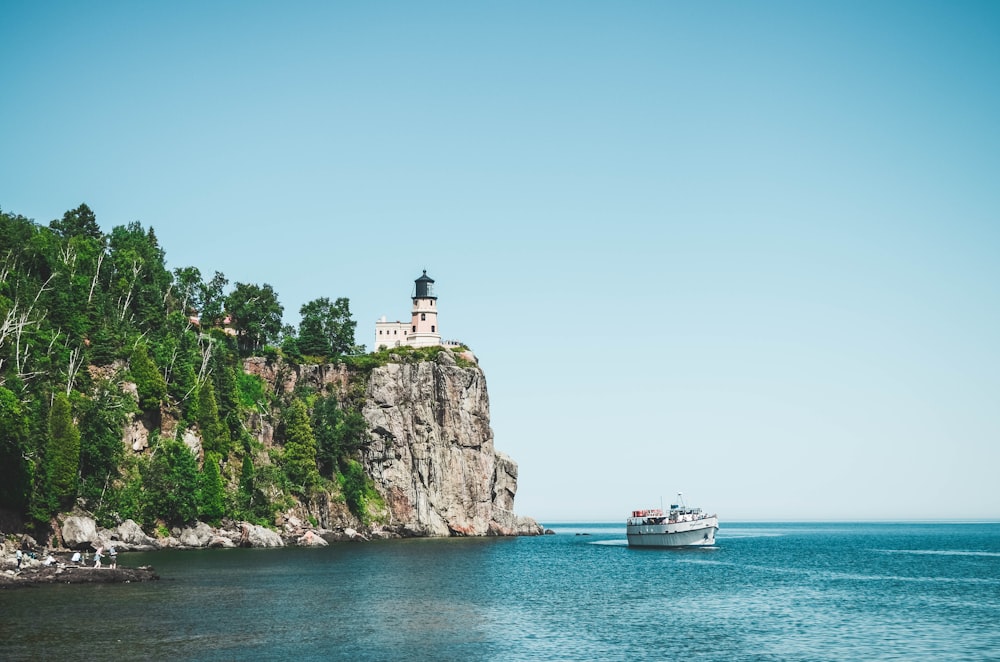 lighthouse on rock formation near calm water