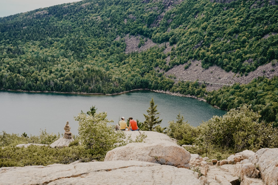 two person sitting on gray rock