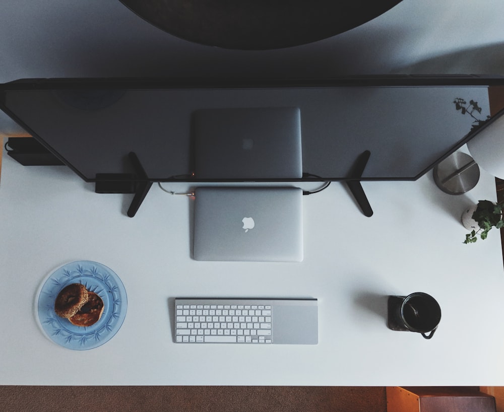 silver MacBook with Magic Keyboard and flat screen TV