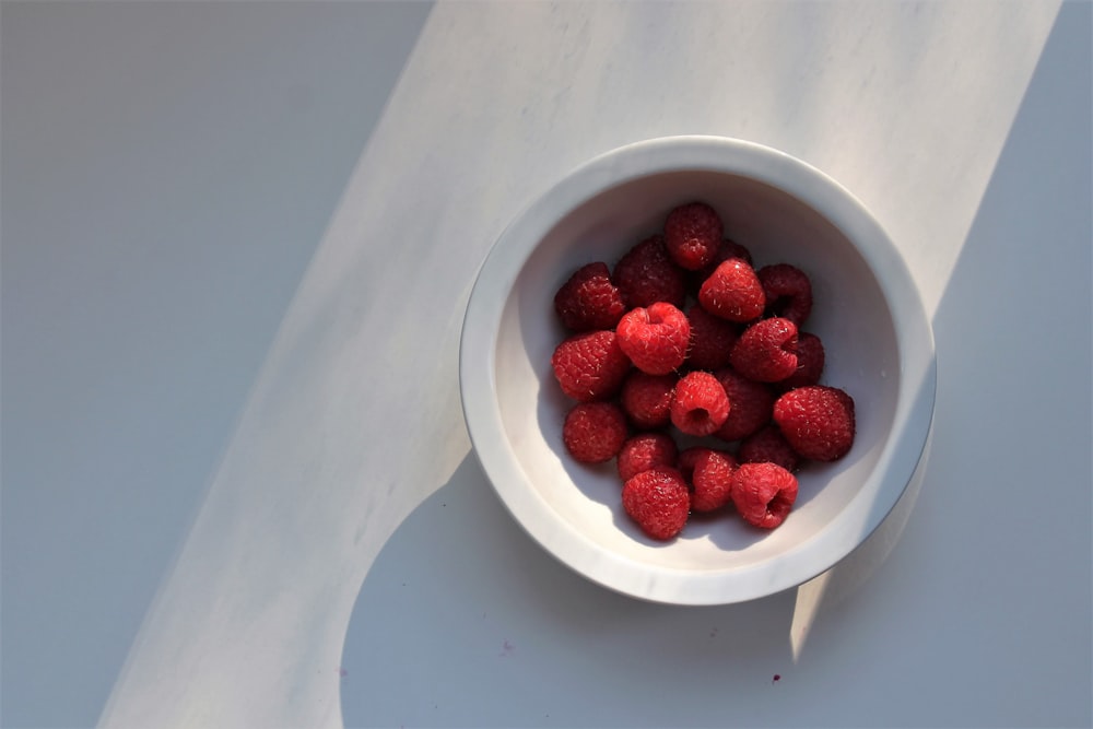 red raspberries on white ceramic bowl