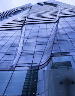 A tall, modern skyscraper with a sleek, glass facade. The building's design features smooth, curved lines and a reflective surface that creates a futuristic and dynamic appearance.
