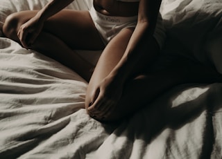 woman wearing white sports bra sitting on bed