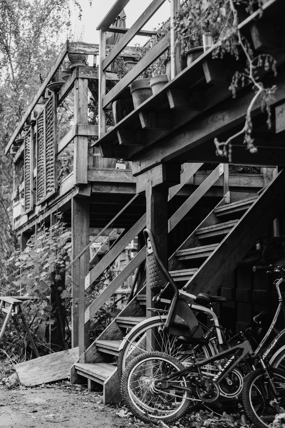 grayscale photography of bicycles under wooden stairs