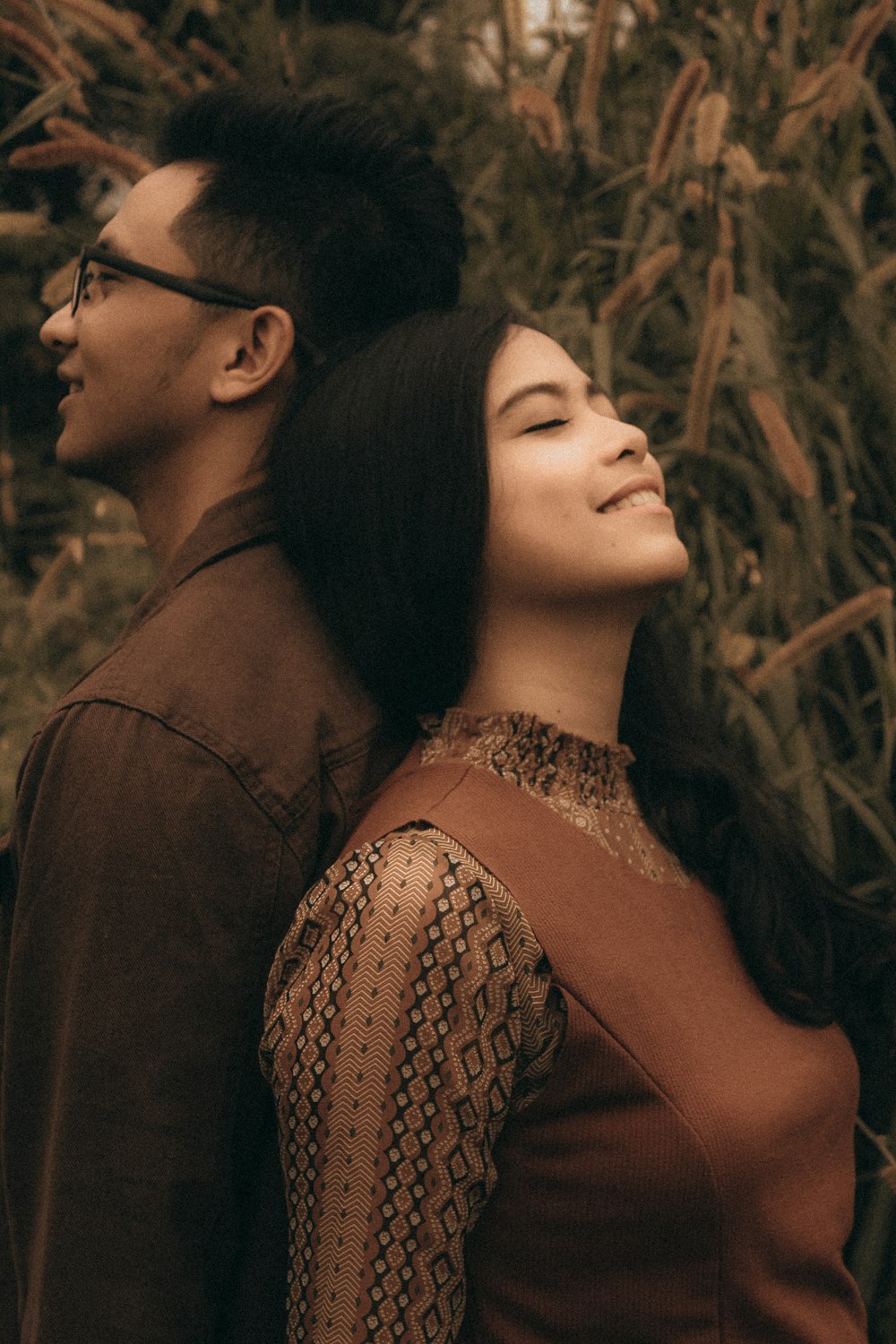 smiling man and woman standing back to back