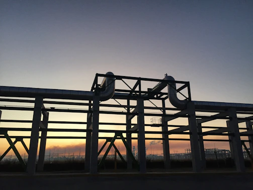 Close-up of oil refinery pipes and valves with a sunset backdrop.