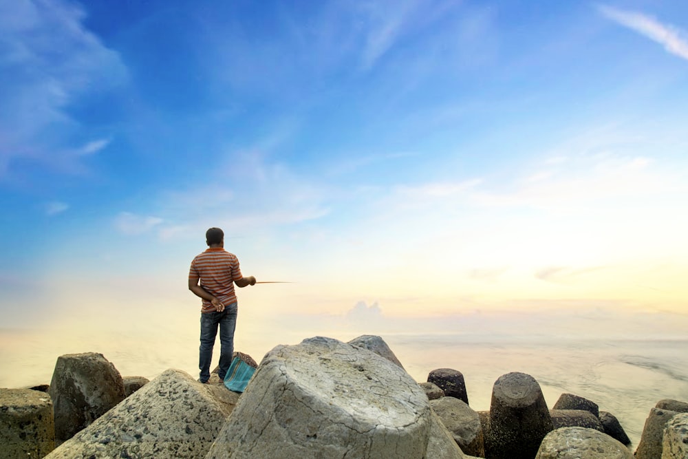 woman standing on big rocks overlooking body of water