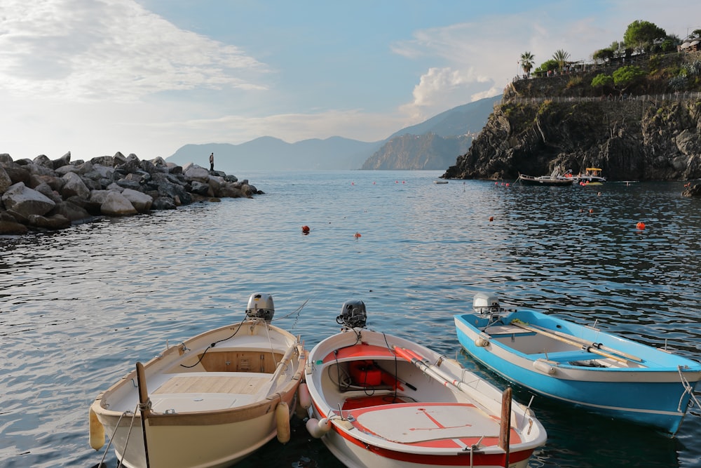 three boats with different colors on body of water