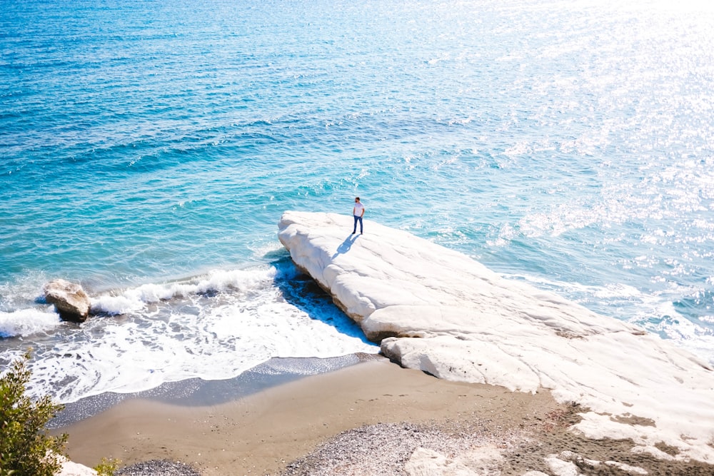 person standing on rock near body of water