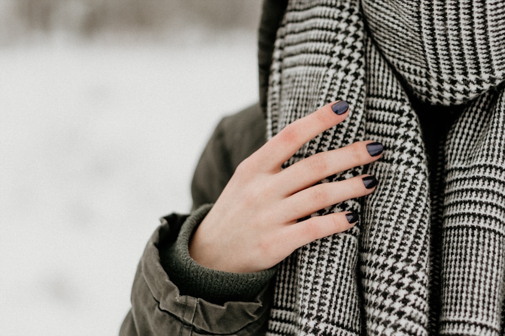 selective focus photography of person wearing black and white houndstooth scarf