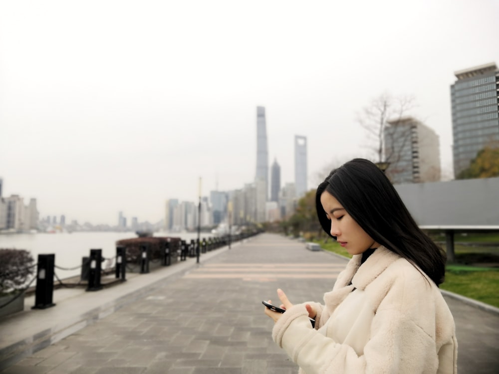 스마트폰을 사용하여 양털 재킷을 입고 있는 여자