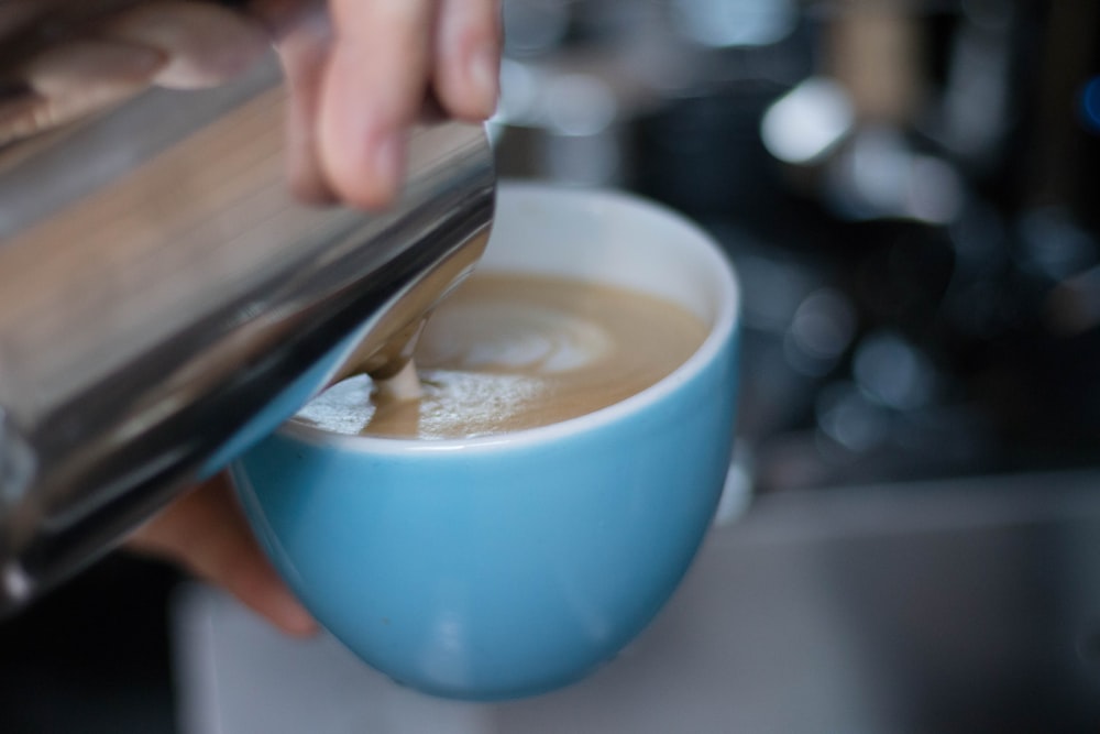 person pouring milk on cup