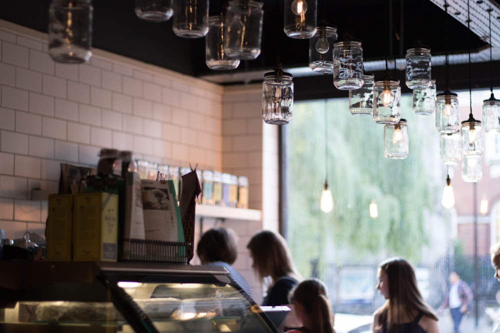 people inside restaurant with Mason jar pendant lamps