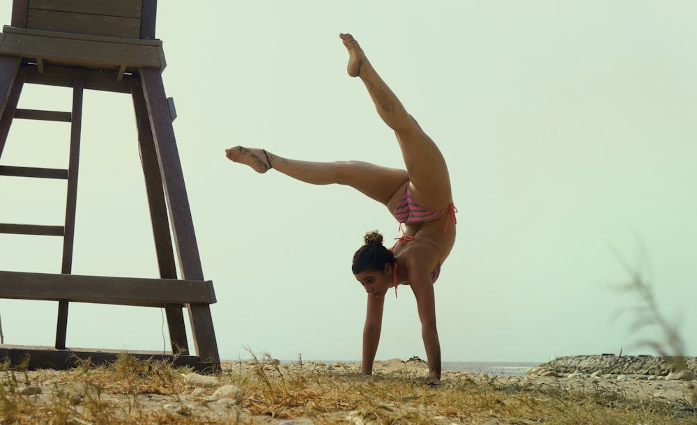 Frau im rosa Bikini macht Handstand