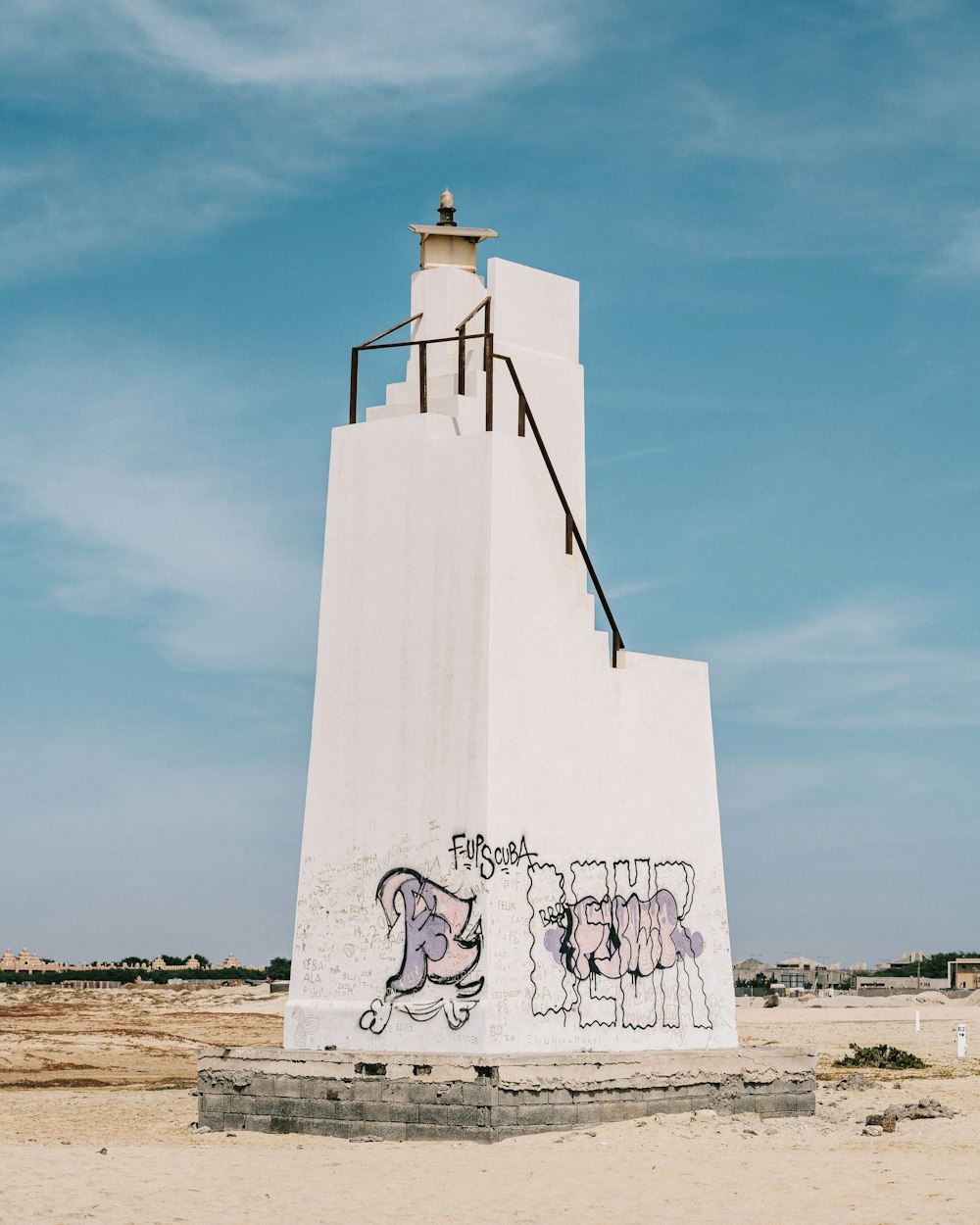 white concrete tower in the middle of sandy terrain during daytime