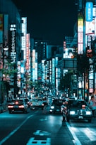 vehicles on roadway between lighted buildings at night
