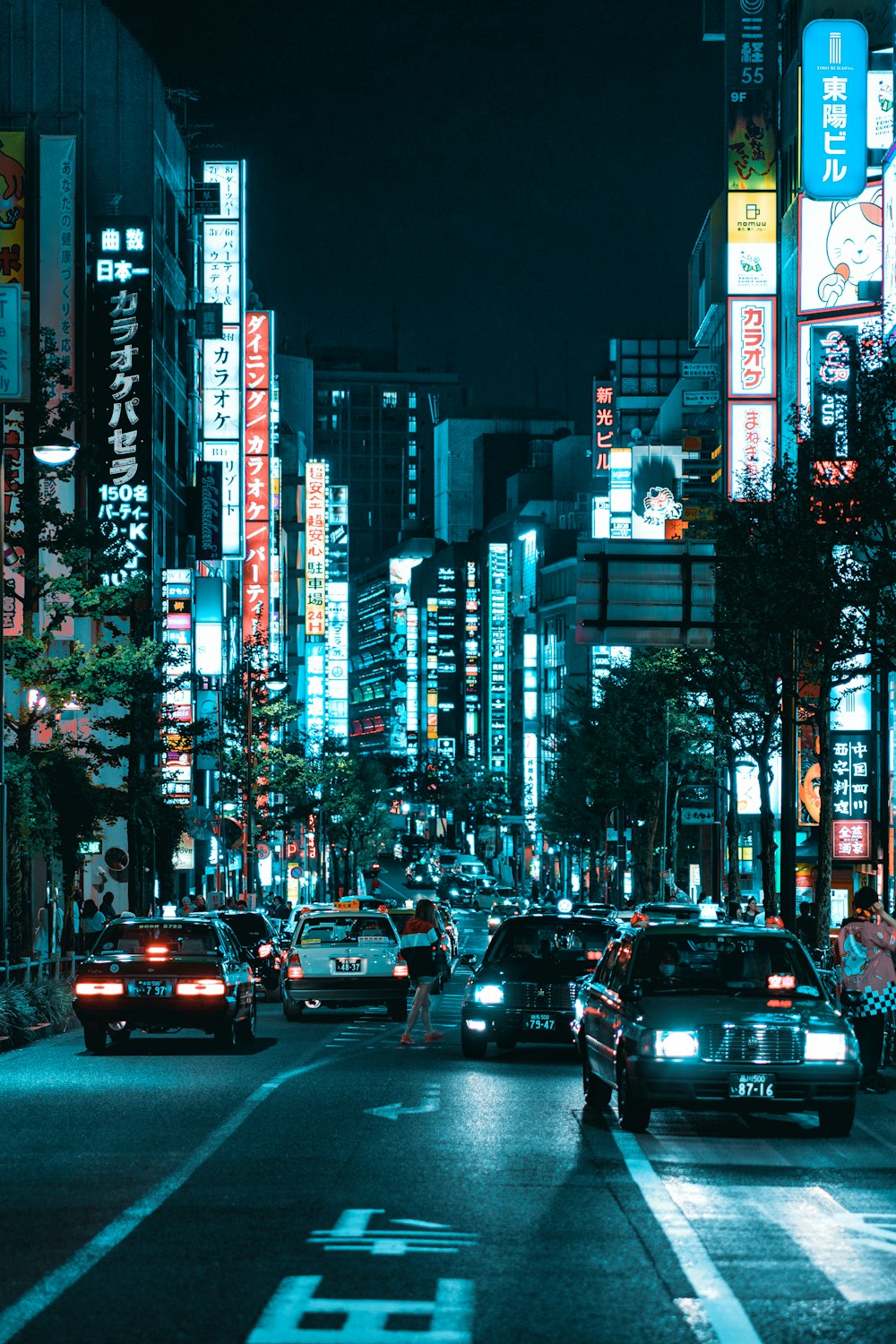 vehicles on roadway between lighted buildings at night