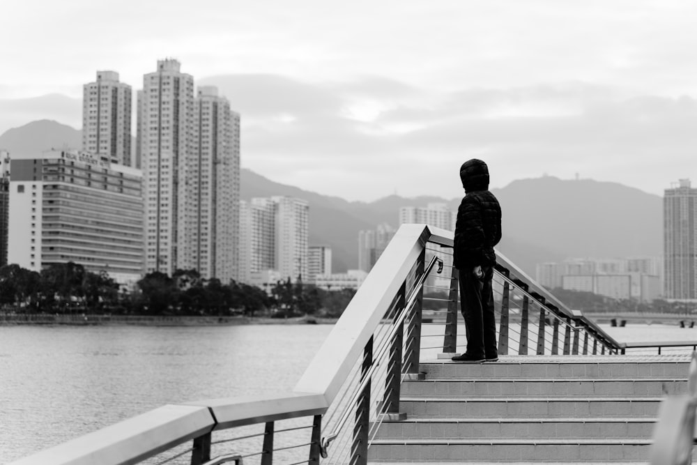 grayscale photography of person standing front of calm water