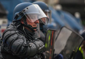 A tactical anti-riot suit displayed on a mannequin, highlighting reinforced padding and integrated communication gear.