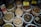 Various types of dried herbs and roots are displayed in large, open plastic bags, each containing a different kind of herb or root. Some bags have labels with prices written in Chinese characters. The image is likely taken in an herbal market or shop.