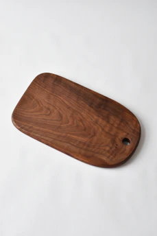 A polished wooden cutting board resting on a rustic kitchen countertop.