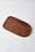 A wooden cutting board with a smooth finish and rounded edges lies on a plain white surface. The wood grain and rich brown color are prominent, with a circular hole near one end.