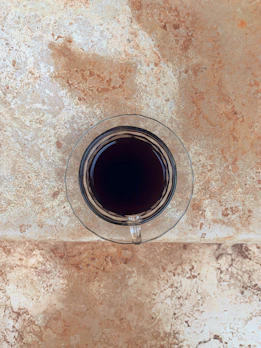 Close-up of a steaming cup of dark coffee beside a rune-inscribed stone.