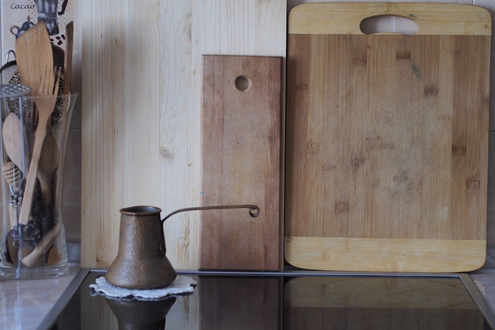 brass cezve pot by chopping boards leaning on wall