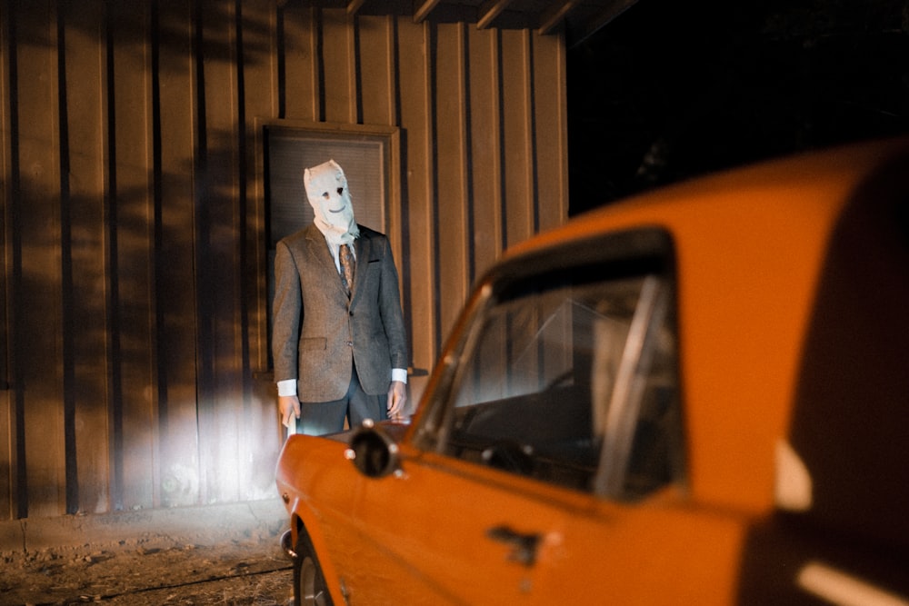 man with mask in front of car