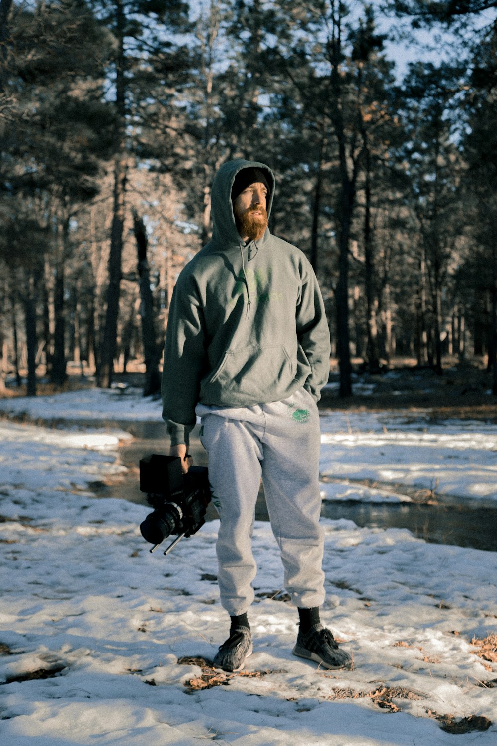 man in gray jacket holding black professional camera