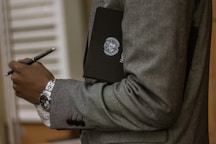 man holding black book and pen