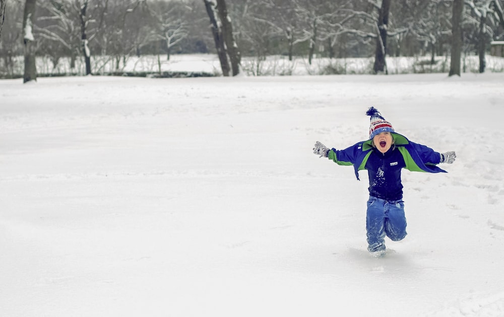 boy running on snow while opening his mouth