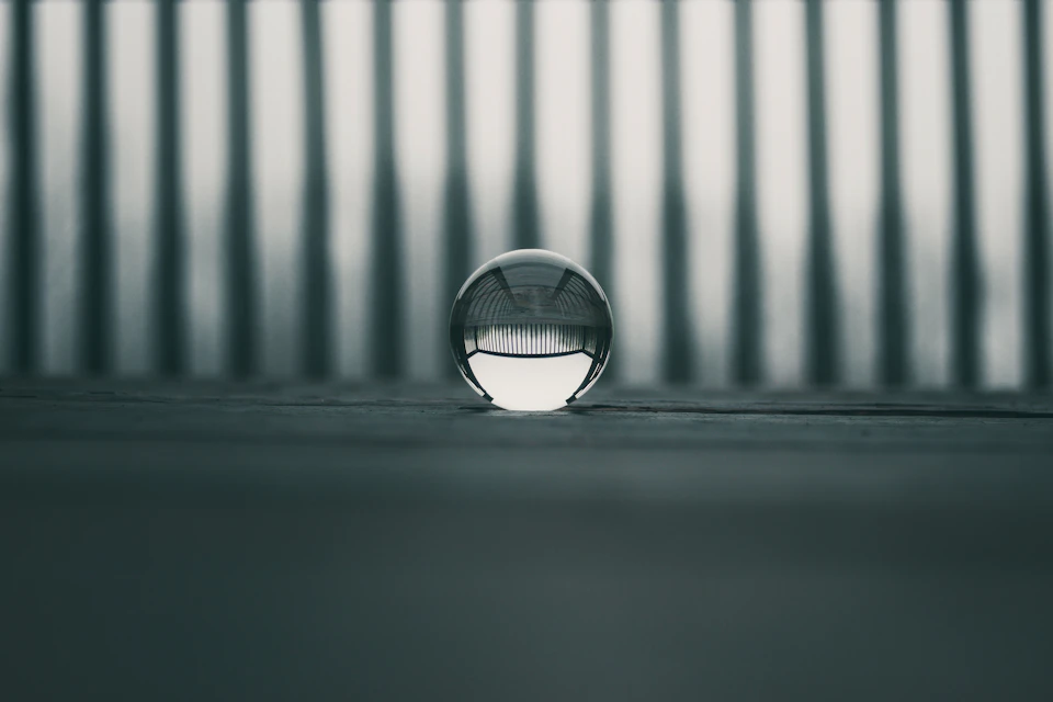 Round glass ball rests on a wooden surface with reflective properties creating an illusion