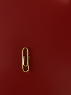 A close-up of hands attaching a paperclip to a colorful printed website layout.