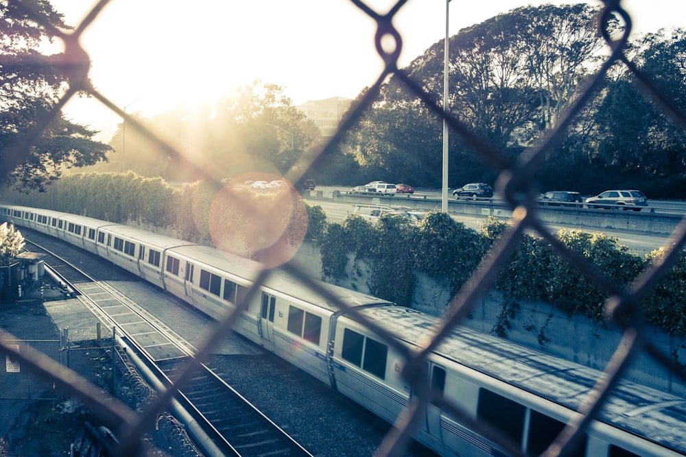 Vue d’un train sur la voie à partir d’une clôture à mailles losangées pendant la journée