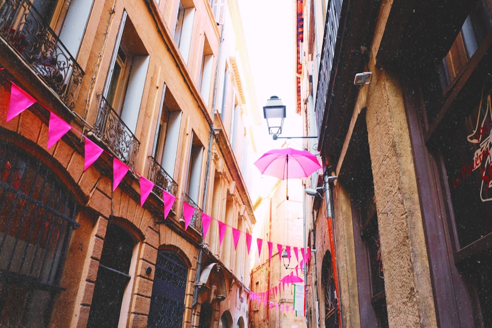 floating pink umbrella near wall lamp