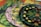 A collection of vibrant, patterned plates with tropical designs including leaves, bananas, and flowers. The plates are stacked in a layered manner, each having distinct colors and patterns featuring lush green foliage and detailed floral motifs.